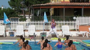 Piscina con gente nadando y una persona haciendo ejercicios.