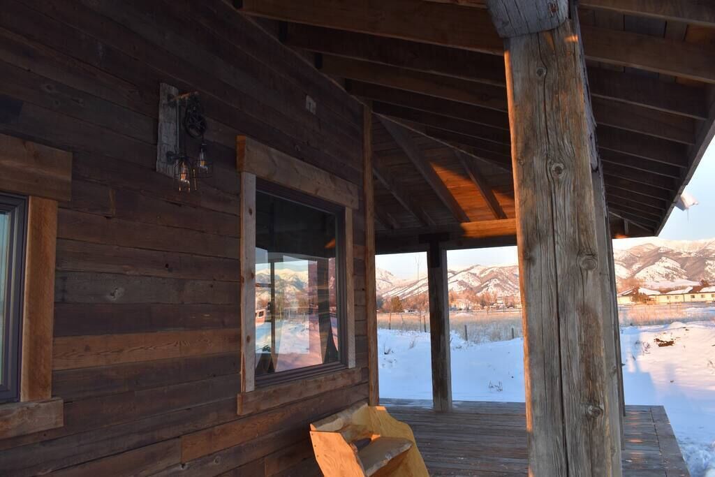 A wooden cabin with large windows overlooking a snowy landscape.