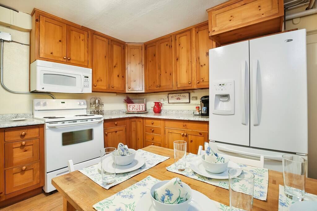 A kitchen with wooden cabinets, a white refrigerator, a microwave, and a stove.