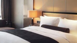 A hotel room with a large bed, a nightstand, a lamp, and a view of the outdoors.