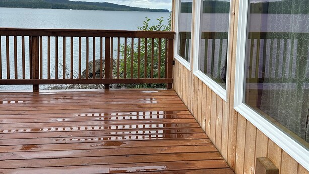 A wooden deck with a view of a lake and mountains.
