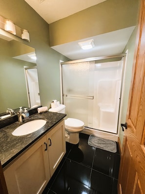 Un baño con lavamanos, inodoro y ducha con mampara de vidrio.