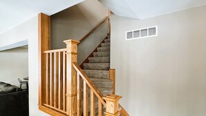 Un escalier avec des rampes en bois et des marches recouvertes de moquette, menant à l’étage supérieur.