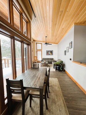 A spacious room with a large wooden dining table, multiple chairs, a sofa, and a ceiling fan.