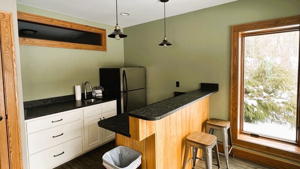 Une cuisine moderne avec des meubles en bois, un plan de travail noir et un ventilateur de plafond.