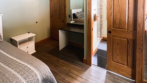 Une chambre à coucher avec un lit, une table de chevet, un bureau et un miroir.