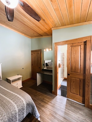 Un dormitorio con cama, mesita de noche, escritorio y espejo.