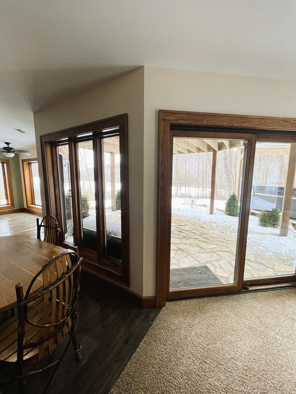 A dining area with a wooden table and chairs, large windows, and a view of a snowy outdoor area.