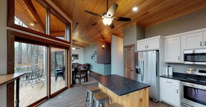 A modern kitchen with wooden beams, a large island, and stainless steel appliances.