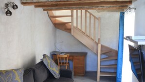 Une pièce avec un escalier en bois, un bureau, une chaise et un canapé.