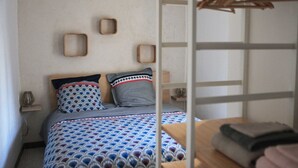 Une chambre à coucher comprenant un lit, une tête de lit en bois, une table de chevet et un porte-vêtements suspendu.