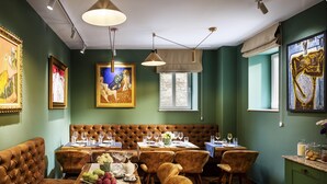 A restaurant with a green wall, wooden flooring, and a brown leather booth. Tables are set with wine glasses and plates. - Gallery 37 (Plovdiv)