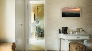 A hotel room with a desk, a chair, a sofa, and a painting of a sunset. - Gallery 37 (Plovdiv)
