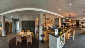 Eine moderne Hotelhalle mit Bar im Zentrum, Sitzgelegenheiten und einer Rezeption.