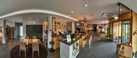 A modern hotel lobby with a central bar area, seating arrangements, and a reception desk.