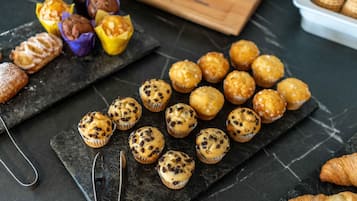Verschiedene Backwaren auf einer Schiefertafel, darunter Muffins und Croissants.