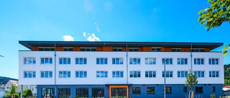 A modern multi-story building with a flat roof, large windows, and a central entrance.