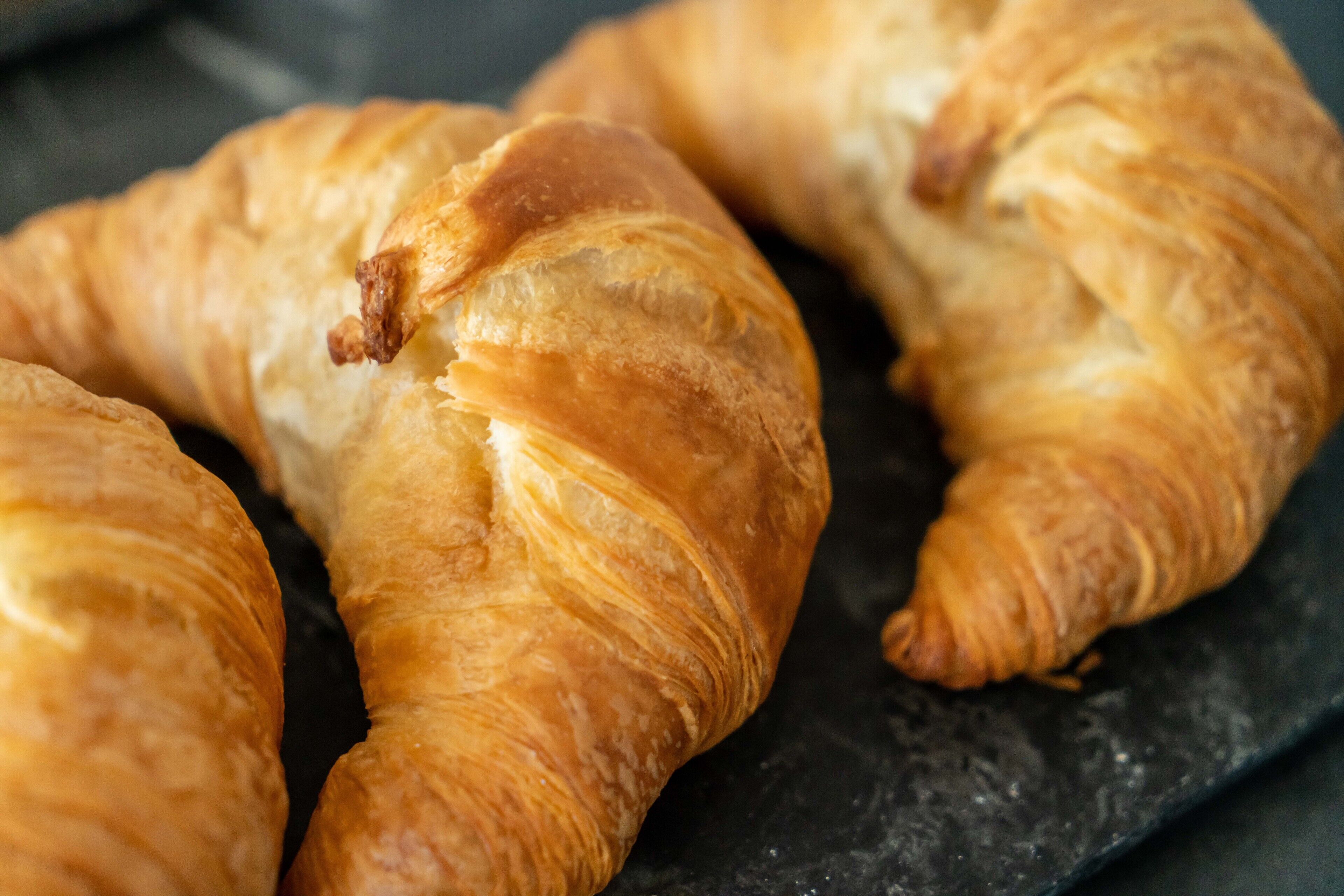 Tres croissants daurats sobre una superfície fosca.