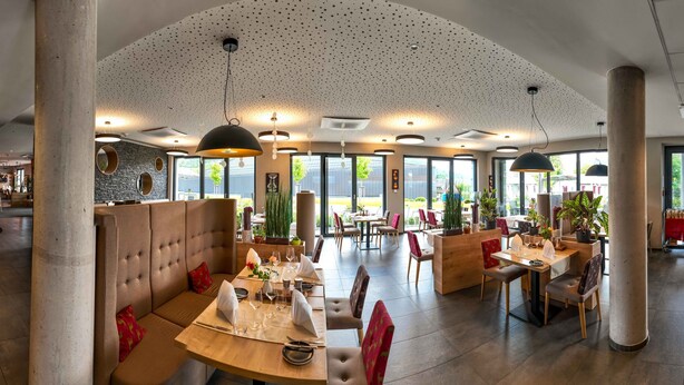 Ein geräumiges Restaurant mit hohen Decken, großen Fenstern und moderner Beleuchtung.