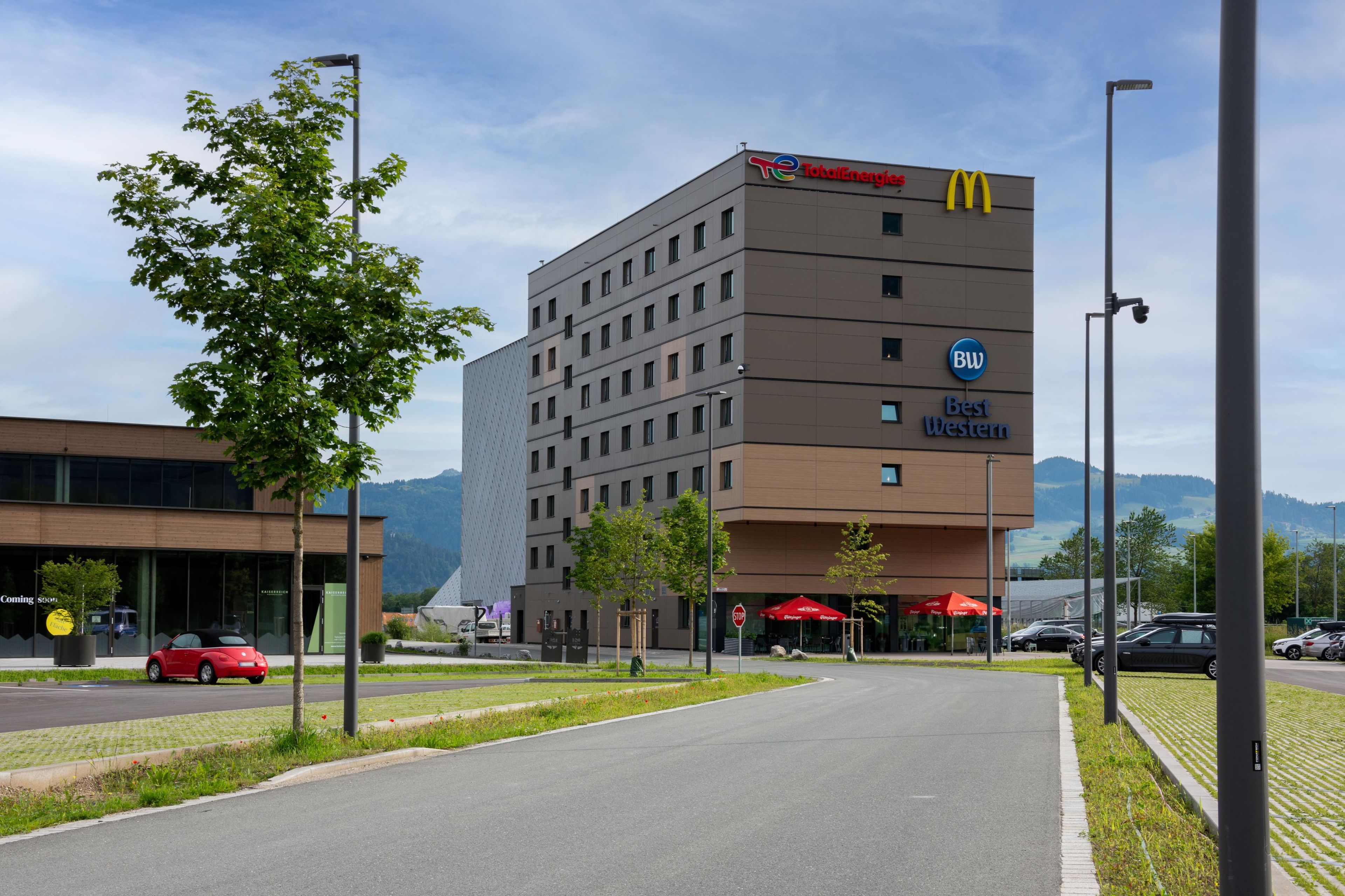 A hotel with a McDonald's sign, a Best Western logo, and a TotalEnergies sign.