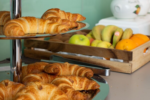 Una exhibición de pasteles y frutas sobre una barra.