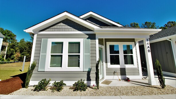 A two-story house with a front porch, a garage, and a well-maintained lawn. - Beacon Quarters by KEES Vacations (Corolla)