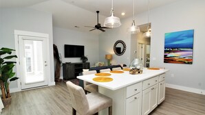 A modern kitchen with a central island, pendant lights, and a dining area with chairs. - Beacon Quarters by KEES Vacations (Corolla)