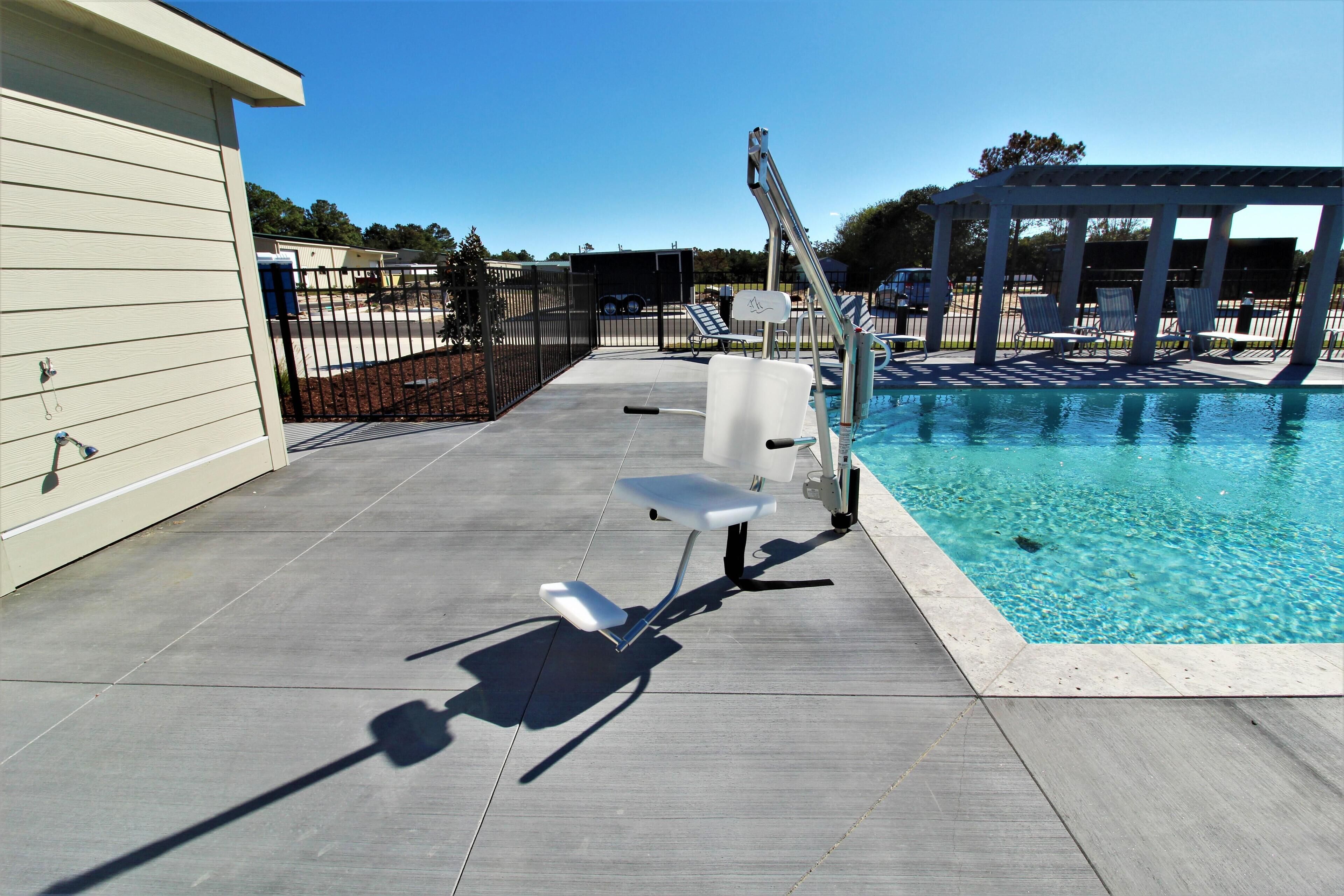 A poolside area with a pool, lounge chairs, and a pergola.