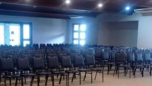A spacious hall with rows of black chairs, a tiled floor, and a wooden ceiling with recessed lighting. - Santa Maria Hotel (Acailandia)