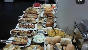A buffet table with various food items including rolls, pastries, and a variety of dishes. - Santa Maria Hotel (Acailandia)