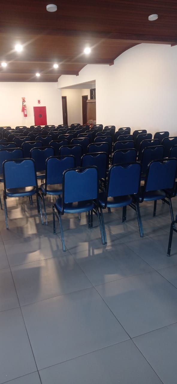 A room with rows of blue chairs, a tiled floor, and a wooden ceiling.