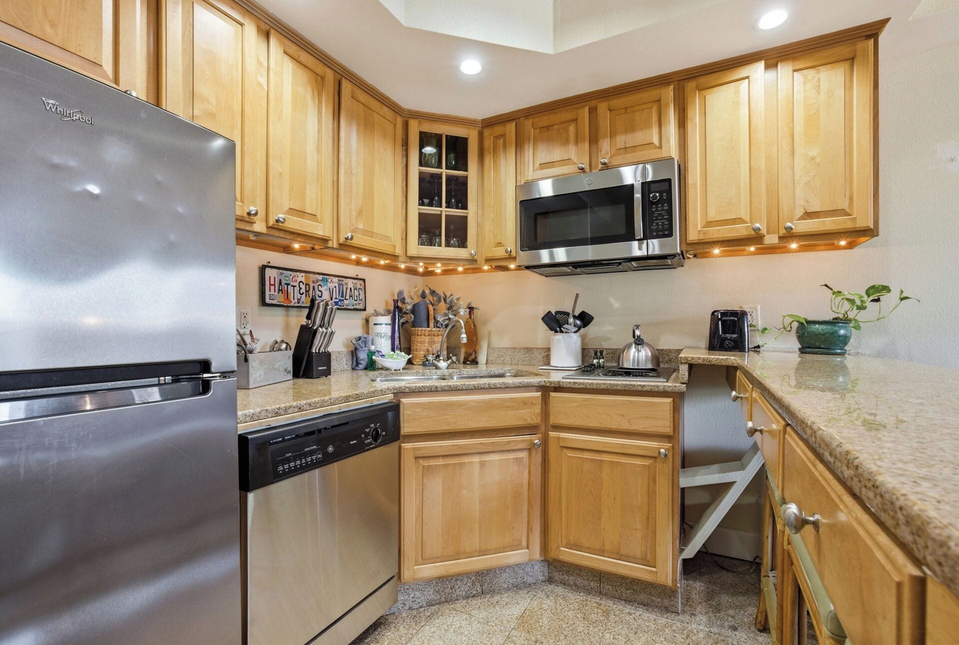 A kitchen with wooden cabinets, a stainless steel refrigerator, a dishwasher, a microwave, and a toaster.