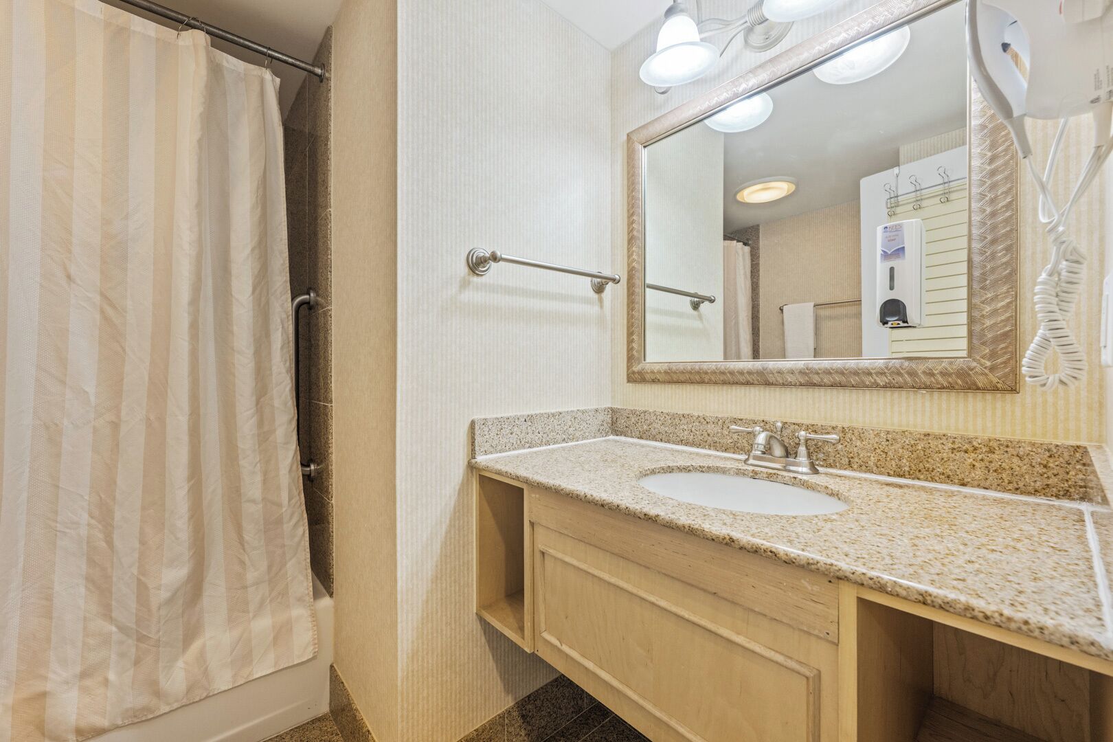 A bathroom with a shower, a sink, a mirror, and a towel rack.