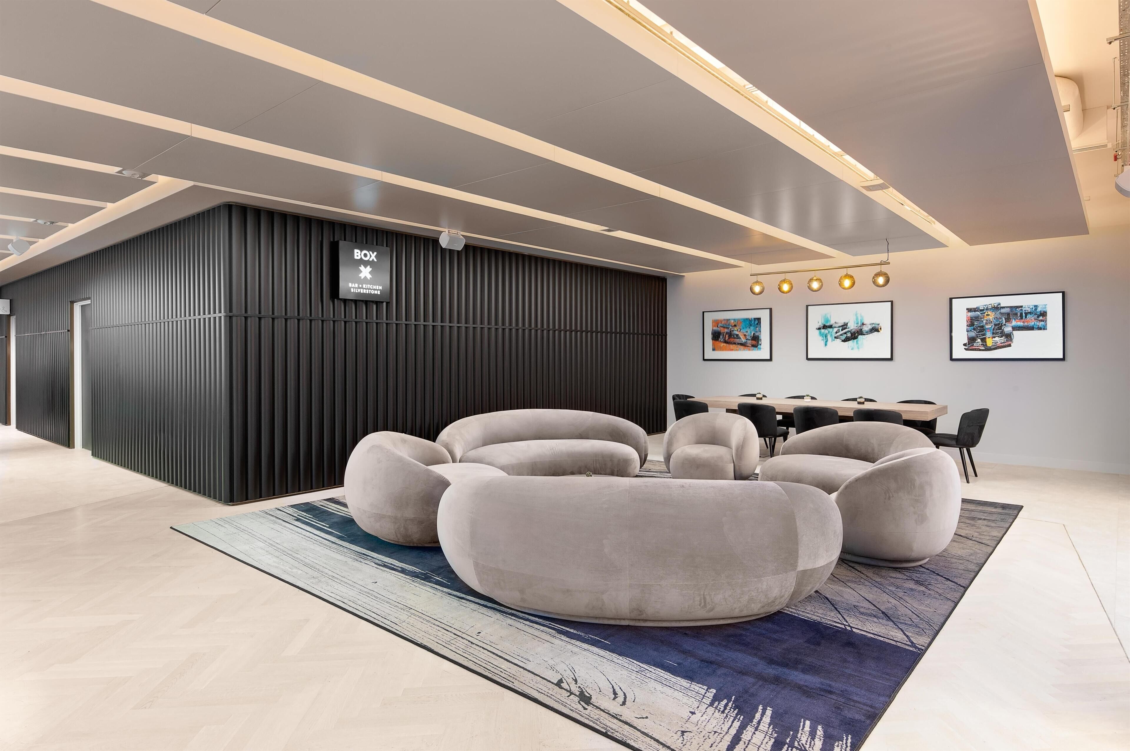A modern interior with a black partition, a seating area with round cushions, and a dining setup with chairs.