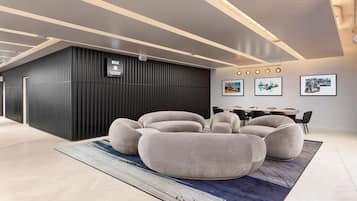 A modern interior with a black partition, a seating area with round cushions, and a dining setup with chairs.