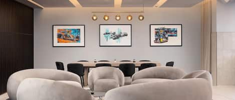 A modern meeting room with a long table, comfortable seating, and artwork on the walls.