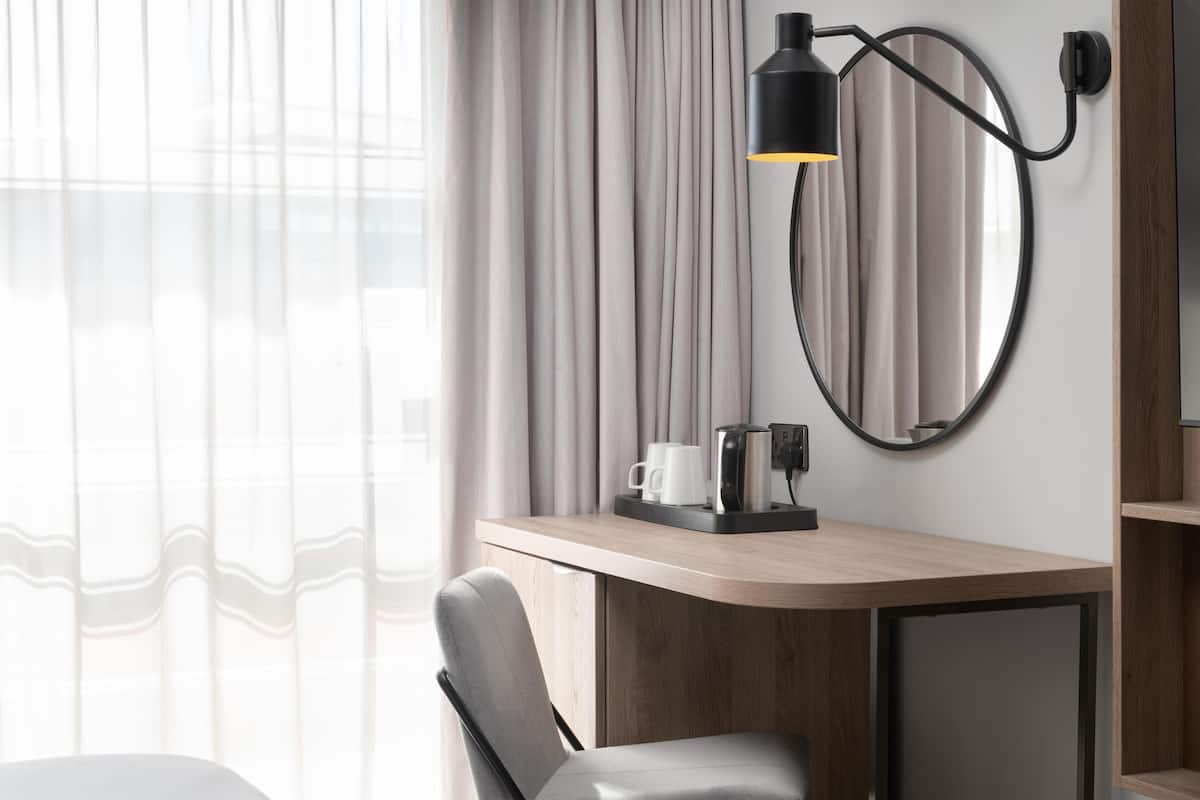 Ein modernes Hotelzimmer mit Schreibtisch, Stuhl und Wandlampe.