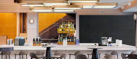 Zona de bar moderna con mostrador, taburetes y una variedad de botellas.