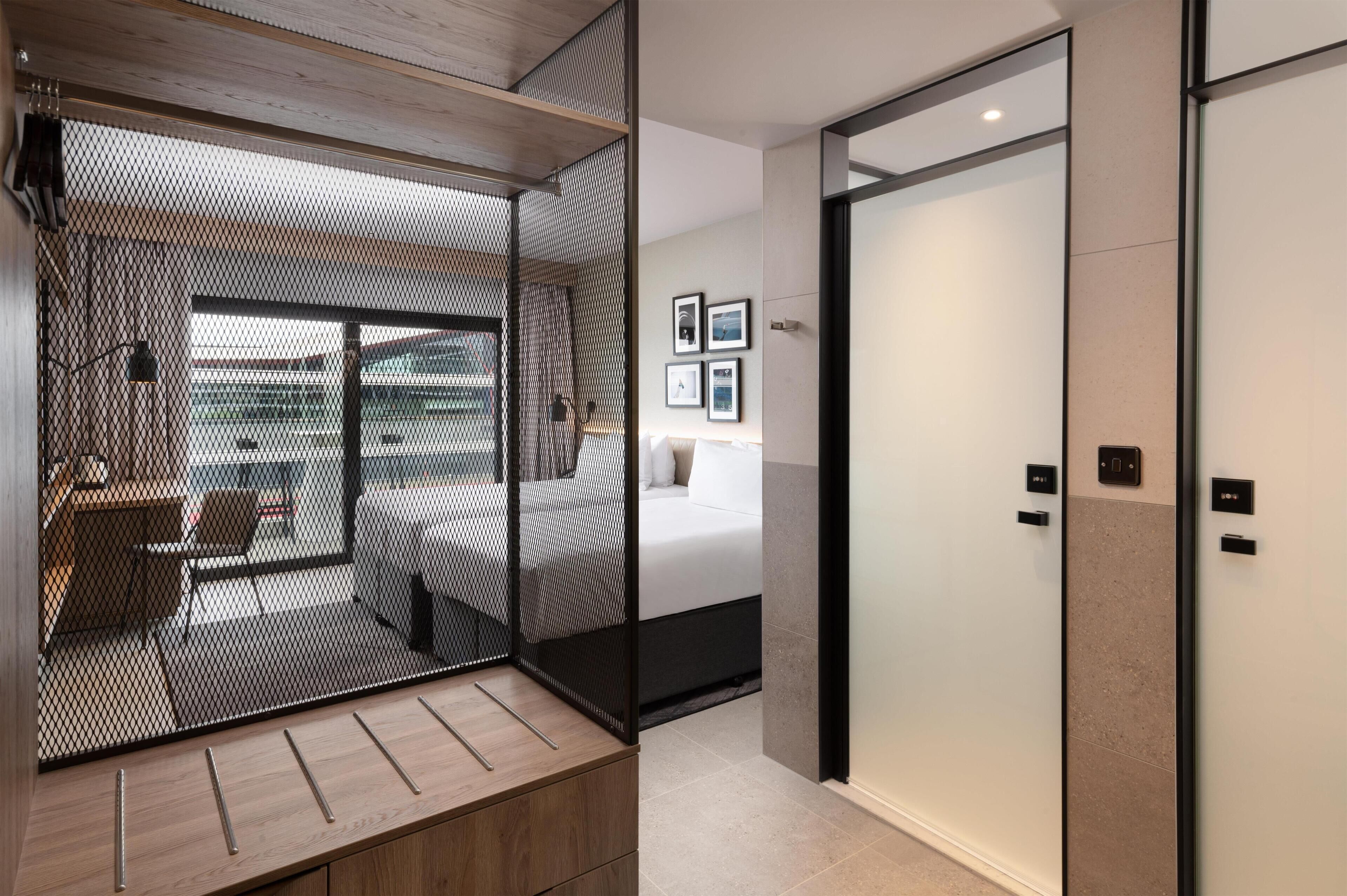 A modern interior with a sliding door leading to a balcony, a bed with a white headboard, and a wall-mounted control panel.