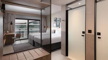 A modern interior with a sliding door leading to a balcony, a bed with a white headboard, and a wall-mounted control panel.