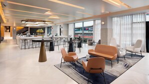 A modern hotel lobby with a bar, seating area, and large windows. - Hilton Garden Inn Silverstone (Towcester)