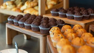 A bakery display with various baked goods, including muffins and pastries, arranged on wooden shelves.