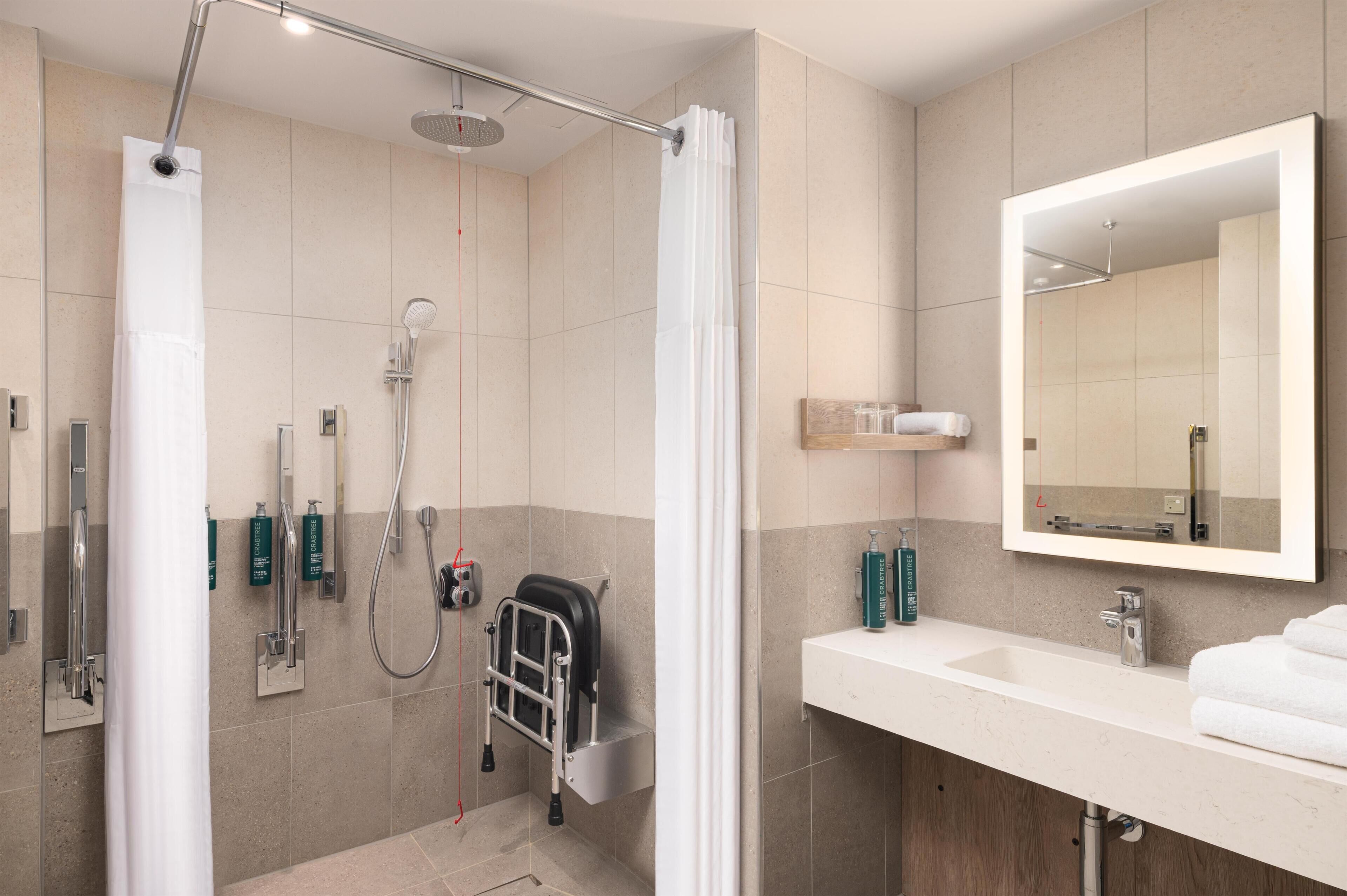 A modern bathroom with a shower, a sink, a mirror, and a towel rack.