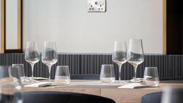 A dining area with a table set for four, glasses, and a framed artwork on the wall.