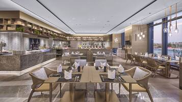Een modern restaurant met een centrale bar, zithoeken en uitzicht op de stad.