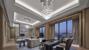 A spacious hotel room with a large desk, comfortable seating, a television, and a city view. - Hilton Beijing Tongzhou (Tongzhou)