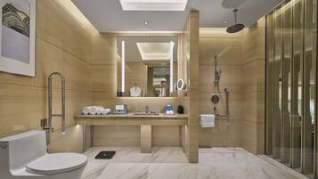 Un baño moderno con inodoro, lavamanos y zona de ducha, que destaca por su suelo de mármol y paredes de madera.