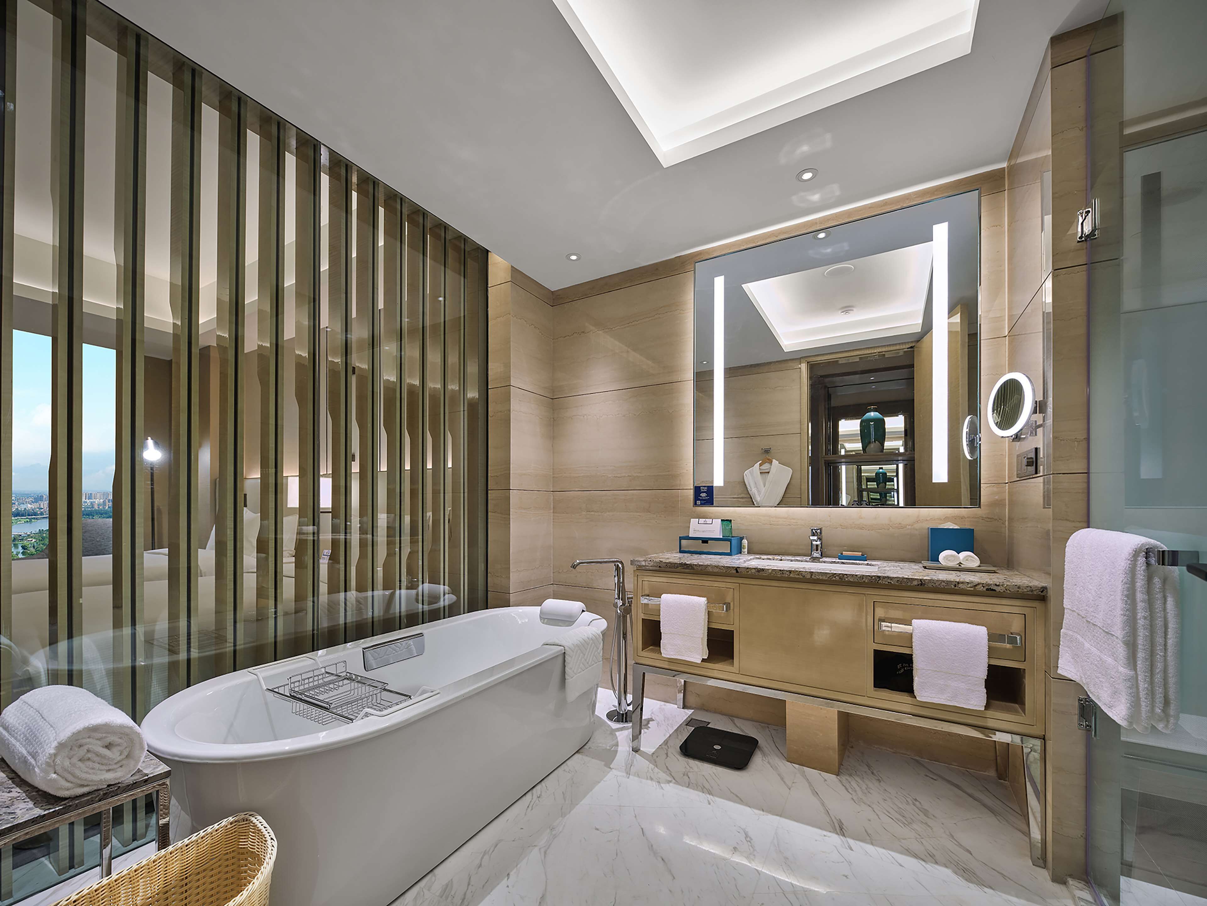 Un baño moderno con una bañera independiente, un tocador con espejo y vistas a la ciudad.