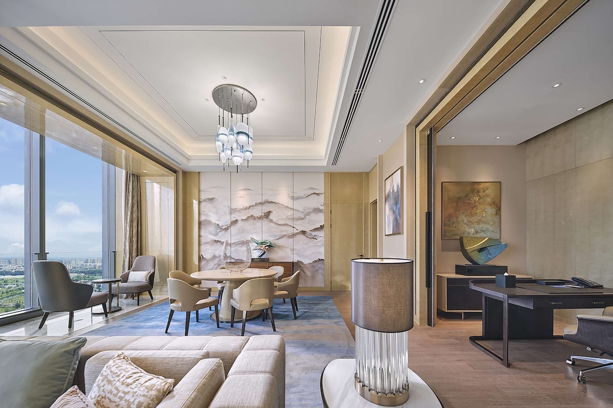 Un interior moderno con zona de comedor, sofá y un amplio ventanal con vista a la ciudad.