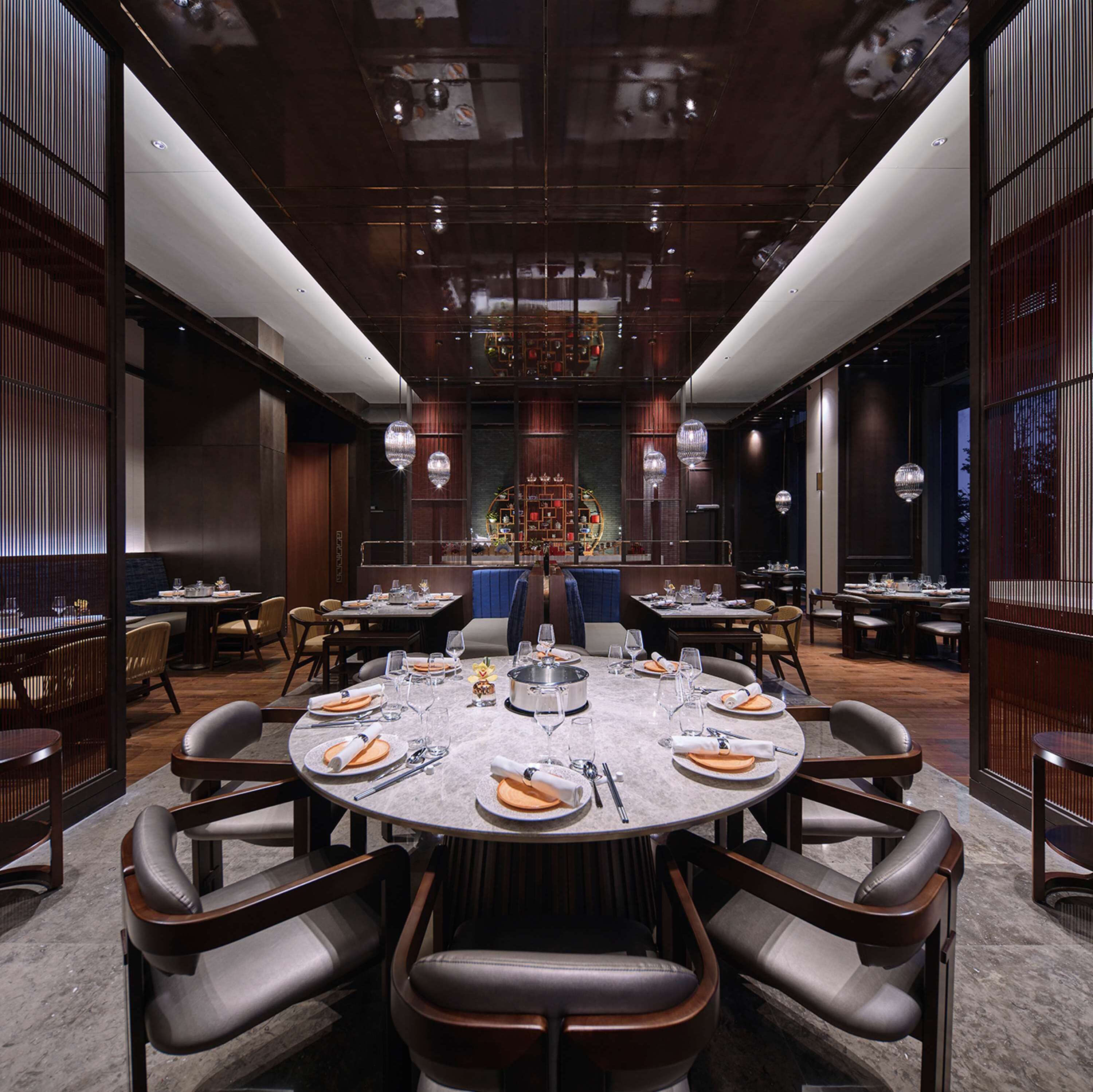 A formal dining room with round tables, leather chairs, and a central decorative element.